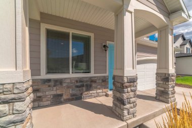 Evin verandasındaki kemerli girişte pencerenin yanında mavi bir kapı var.