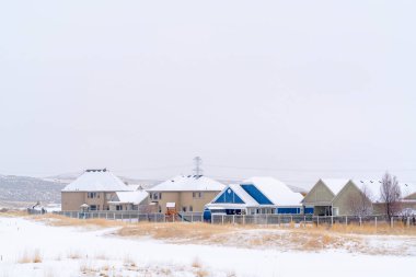 Tepe ve bulutlu gökyüzüne karşı karla kaplı yerleşim yerlerindeki evler