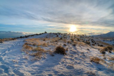 Bulutlu gökyüzünde parlak güneş karlı tepelerin üzerinde ve Utah Vadisi 'nin manzaralı dağlarında