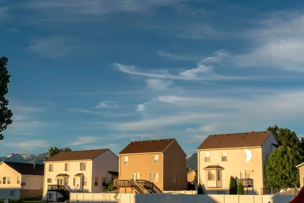 Suburb homes with gable roofs against mountain peak and blue sky with clouds