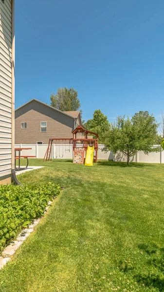 Vertical frame Home backyard with vibrant green grasses lush plants and childrens playground