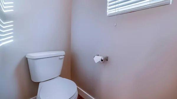 Panorama Toilet at the corner of a bathroom against gray wall with tissue roll holder — Stock Photo, Image