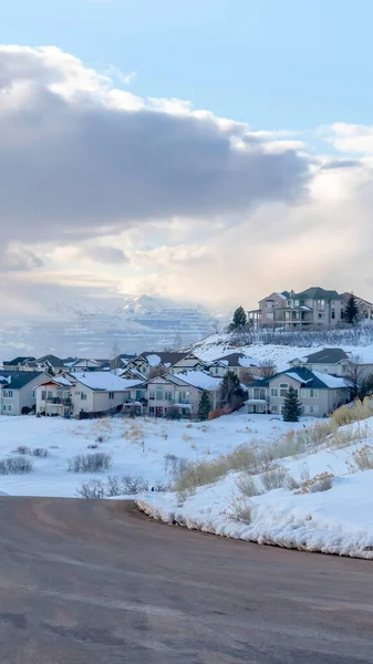 Cultivo vertical Camino curvo en la montaña nevada con casas contra el cielo azul nublado — Foto de Stock