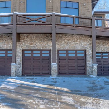 Park City Utah mahallesindeki karlı bir evin balkonunun altındaki kare çerçeveli garaj kapısı.