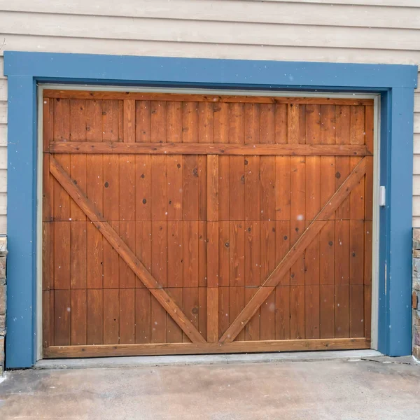 Square Brown wood garage door with blue frame flaned by wall mounted vintage lanterns — Stock Photo, Image