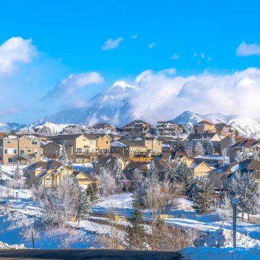 Güneşli bir kış gününde karlı Wasatch Dağı arazisinde evleri olan güneşli bir kasaba.