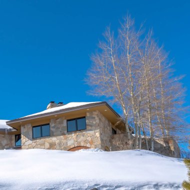 Park City Utah 'ta bir tepenin üstündeki karlı kalça çatılı, kare çerçeveli ev kışın Utah manzaralı