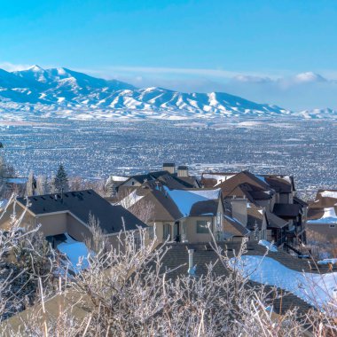 Vadiyi ve Wasatch Dağı 'nı gören karlı yamaçta, kare çerçeveli lüks evler