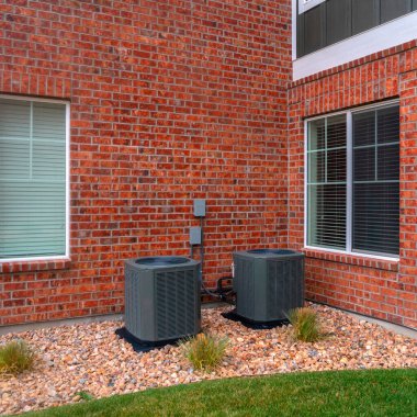 Kare köşeli tuğla duvar, iki kutulu bir binaya.