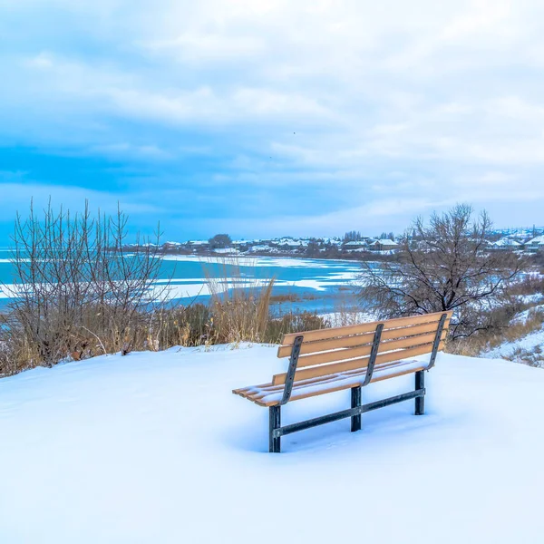 Quadratische Bank auf schneebedecktem Gelände mit gefrorenem Utah Lake und bewölktem Himmel im Winter — Stockfoto