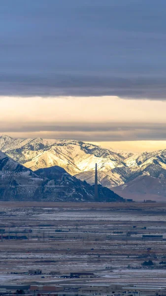 Vista panorámica vertical de Salt Lake City bordeada por una imponente montaña nevada iluminada por el sol — Foto de Stock