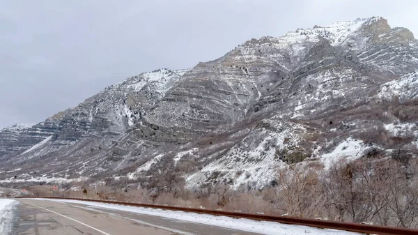 Route panoramique le long de la montagne enneigée escarpée dans Provo Canyon avec un ciel nuageux arrière-plan — Photo