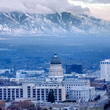 Dik karlı dağ ve gri bulutlu gökyüzüne karşı Utah Eyalet Meydanı Başkenti Binası
