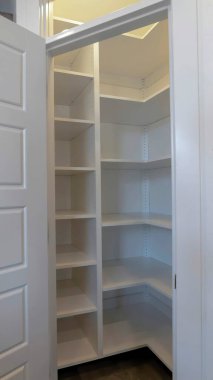 Evin mutfağının köşesinde boş duvar rafları olan küçük bir kiler.