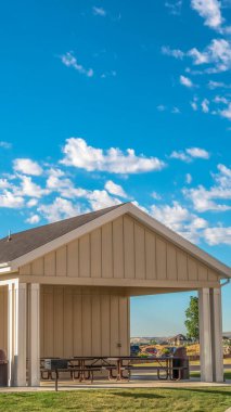 Dağ ve mavi gökyüzüne karşı parka eklenmiş piknik pavyonu olan dikey çerçeve.