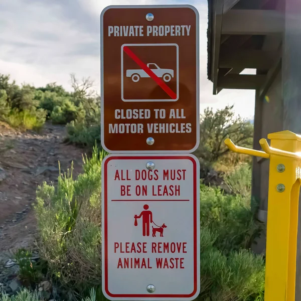 Piazza proprietà privata e cartelli per animali domestici accanto a una stretta strada sterrata su un terreno collinare — Foto Stock