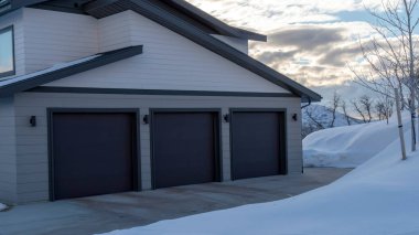 Panorama Home exetrior with paved driveway leading to the three door garage entrance clipart