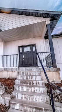 Dikey ekin, kışın açık mavi gökyüzüne ve bulutlara karşı karla kaplı bahçeli ev.