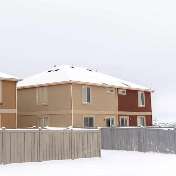 Square crop Homes with hip roofs and wooden fences on a neighborhood blanketed with snow