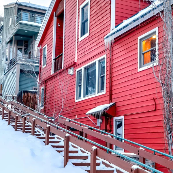 Quadratische Außentreppen und gemütliche Häuser auf einem schneebedeckten Hügel gegen bewölkten Himmel im Winter — Stockfoto