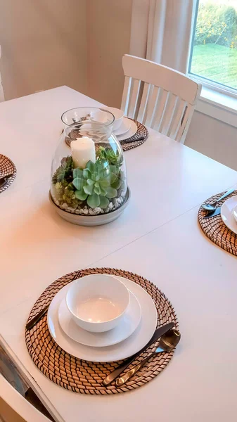 Vertical Dining table with tableware centerpice and chairs against brown wood floor — Stock Photo, Image