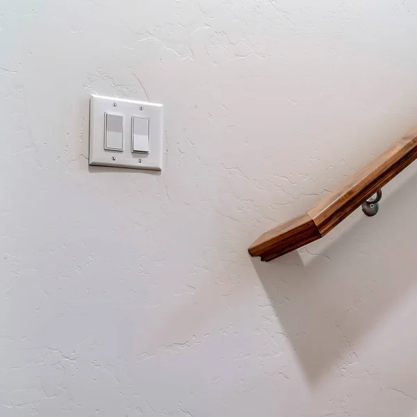 Коричневые деревянные перила лестницы и рокерный выключатель против внутренней стены — стоковое фото