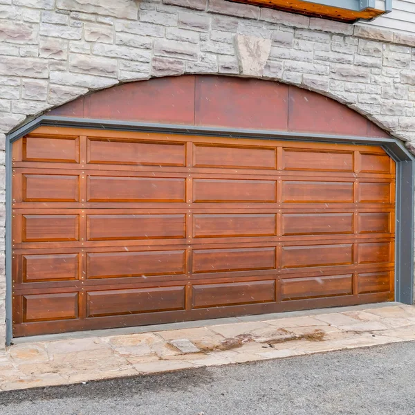 Cadre carré Panneau de bois brun arqué porte de garage de la maison avec mur extérieur en brique de pierre — Photo