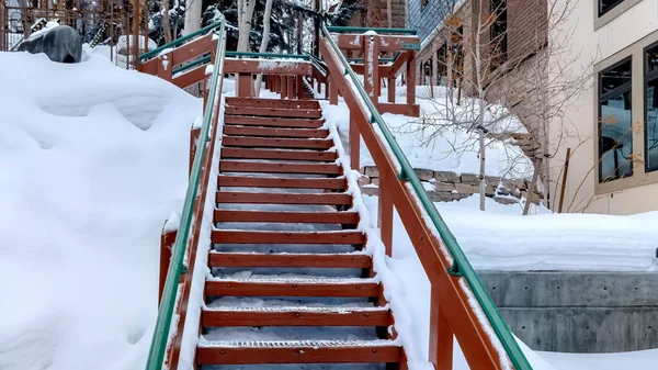 Panorama Outdoor stairs with grate metal treads and green handrail on snowy winter hill