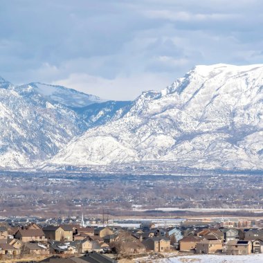 Karla kaplı karla kaplı kare vadi manzarası evler ve göl üzerinde yükseliyor.