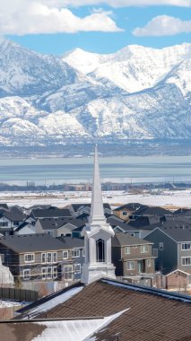 Dikey çerçeve kilise, karlı dağ ve manzaralı göl manzaralı komşu evlere karşı.