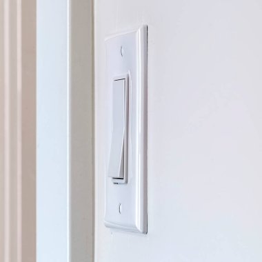 Beyaz iç duvara monte edilmiş elektrikli rockçı ışık anahtarı kare çerçeve yan görünümü