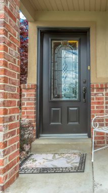 Evin ön cephesinde kırmızı tuğladan duvarlı dekoratif cam camlı dikey ön kapı.