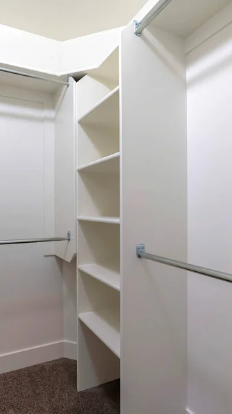 Vertical Hanging metal rods and storage shelves inside empty walk in closet of a new home