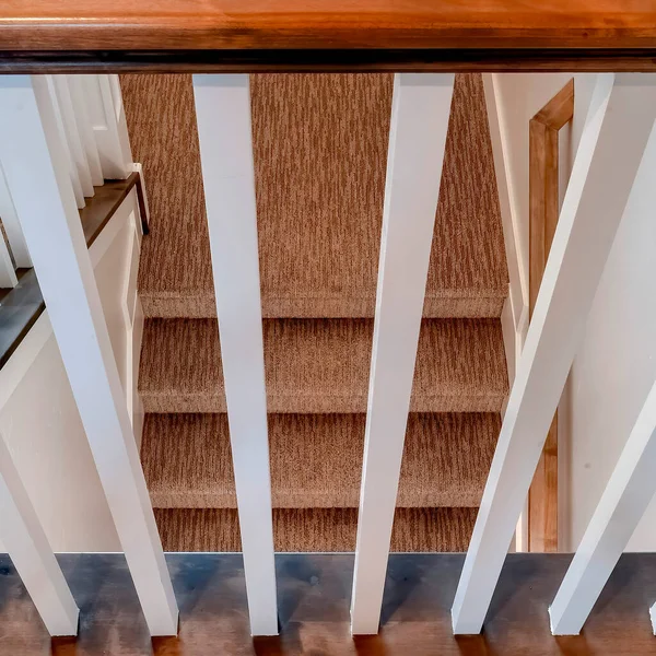 Escalier carré en forme de U avec balustrade blanche marron et tapis sur les marches — Photo
