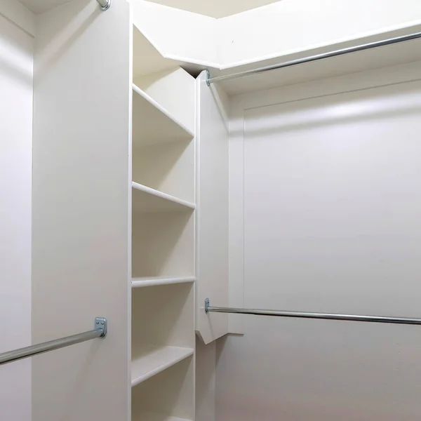 Square Hanging metal rods and storage shelves inside empty walk in closet of a new home