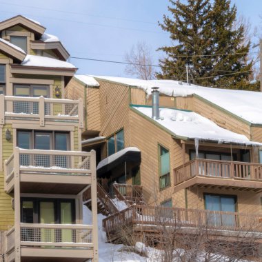 Park City Utah 'ta kış boyunca dağ evlerinin çatılarında kar ve buz saçakları.