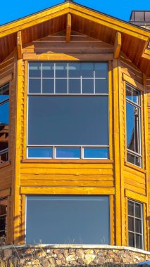 Büyük koy pencereleri ve ahşap dış duvarı olan dikey çok katlı ev cephesi