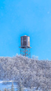 Dikey ekin karları kışın Wasarch Dağlarını mavi gökyüzüne karşı su tankı kulesiyle kapladı