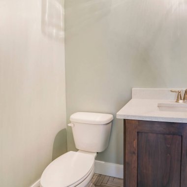 Kare ekin, lavabo ve musluk beyaz tezgahın üzerinde tuvalet yanındaki ahşap dolabın üzerinde.