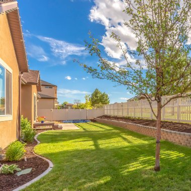 Canlı çimleri olan ve beyaz bahçe çitleri boyunca dikim yatağı kaldıran kare ev bahçesi.