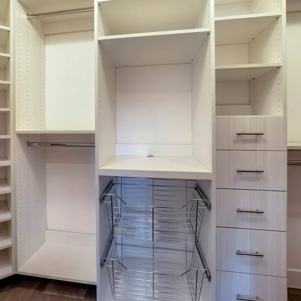 Square Walk in closet interior with shelves hanging rods drawers and metal baskets