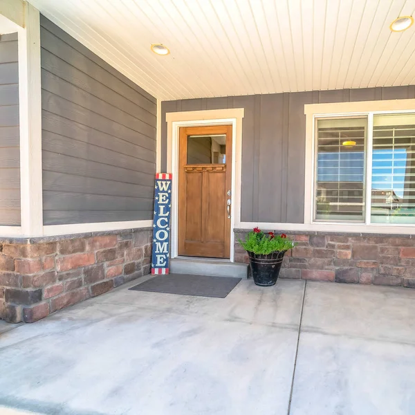 Plaza de entrada a casa con porche de hormigón marrón puerta frontal de madera señal de bienvenida — Foto de Stock