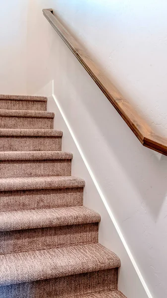 Verticaal frame Vloerbedekking binnen trap van huis met bruine leuning tegen witte zijwand — Stockfoto