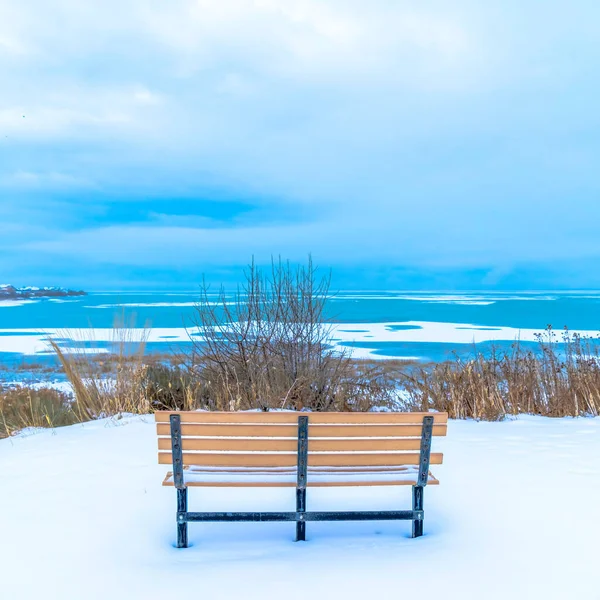 Quadratische Sitzbank mit Blick auf den halb gefrorenen Utah Lake mit bewölktem Himmel über dem Horizont — Stockfoto