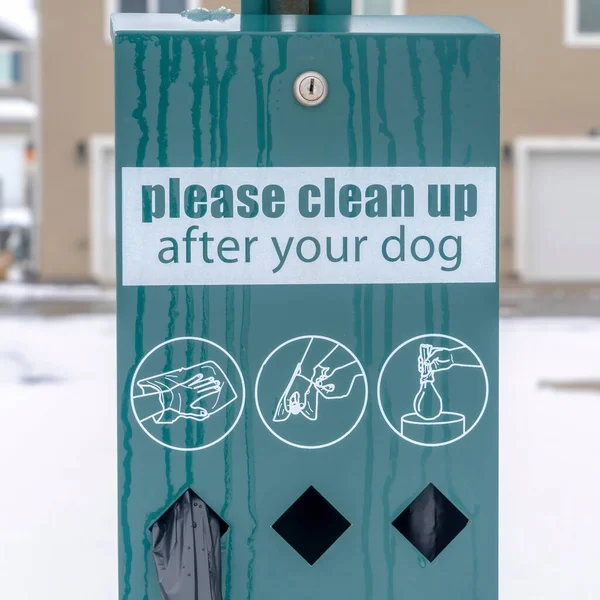 Quadratische Ernte Pet Waste Station mit schwarzen Hundekotbeuteln gegen verschwommene Häuser und verschneiten Boden — Stockfoto