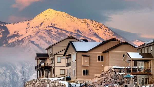 Panorama Houses on hill with scenic view of Wasatch Mountains and cloudy sky at sunset