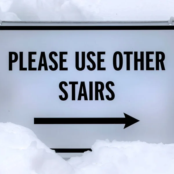 Square frame Sign that reads Please Use Other Stairs against fresh white snow in winter — Stock Photo, Image