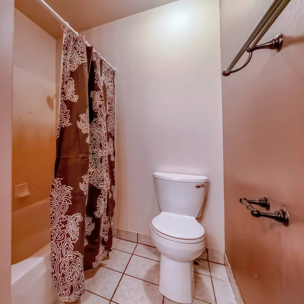 Kare tuvalet ve banyo içinde fayanslı zemin ve duvara asılmış havlu çubukları olan banyo küveti. — Stok fotoğraf