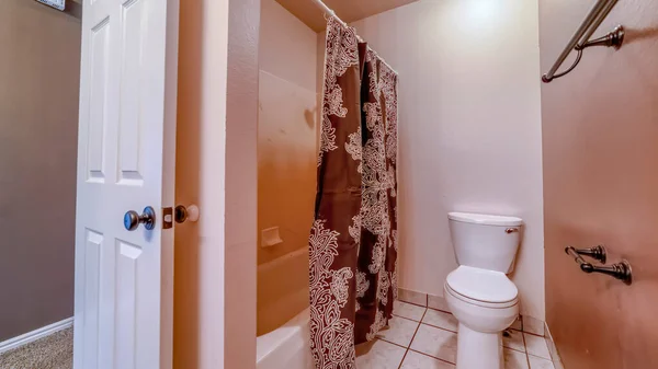 Panorama Toilet and bathtub inside bathroom with tile floor and wall mounted towel rods