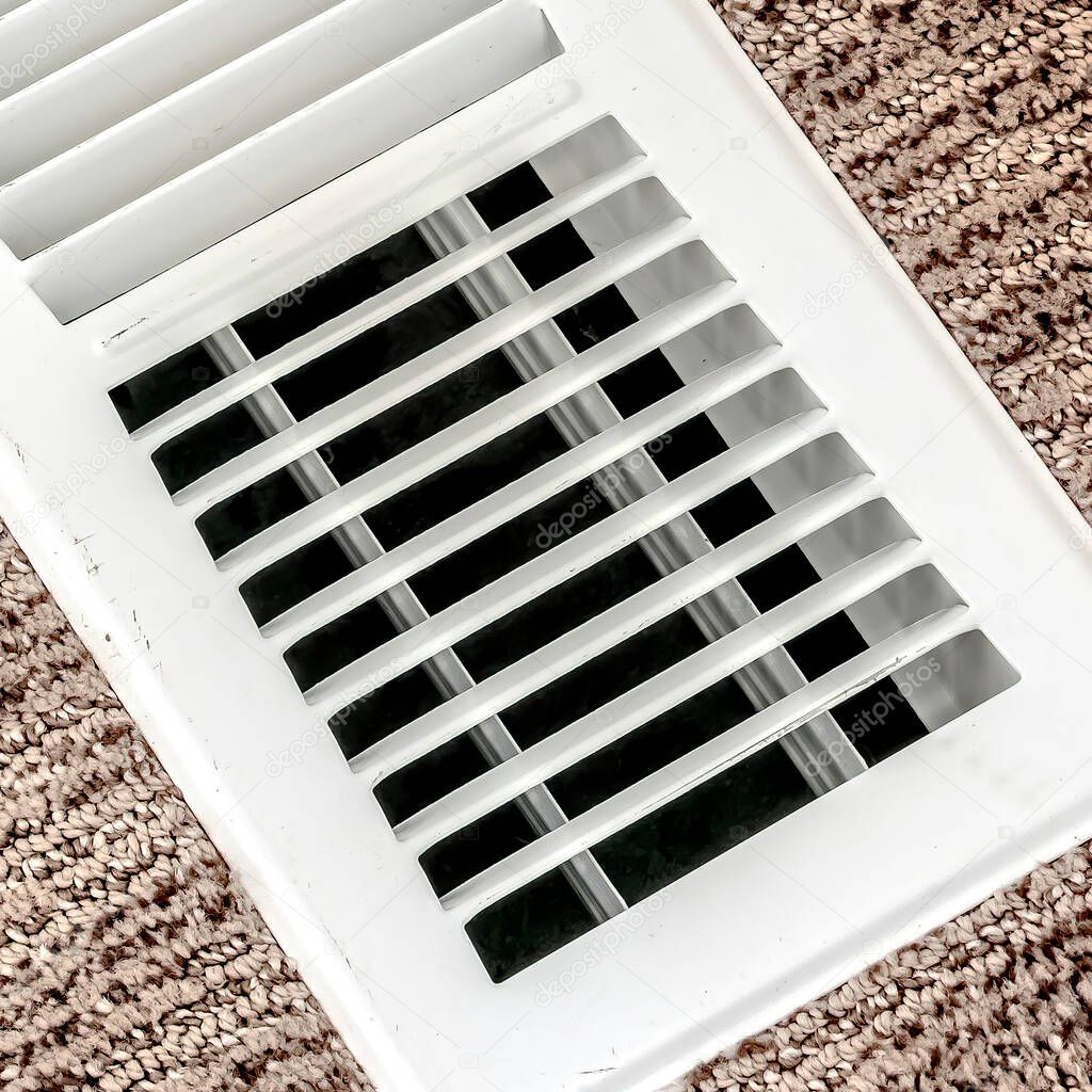 Square White air conditioner duct grille cover against floor with brown carpet